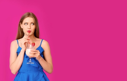 Young woman with glass of delicious milk shake on color background