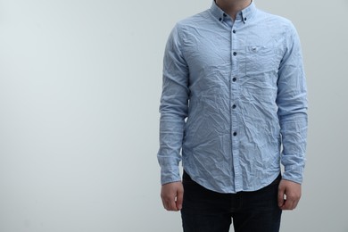Photo of Man wearing creased shirt on light background, closeup. Space for text