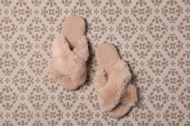 Photo of Fluffy beige slippers on carpet, top view