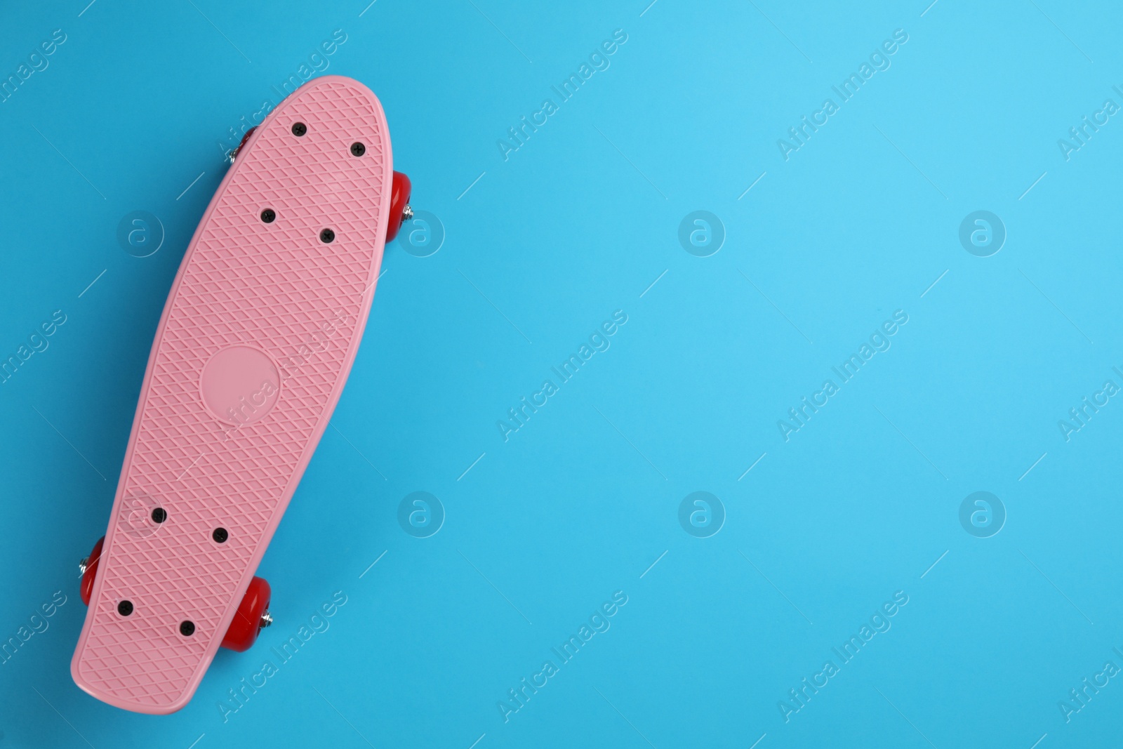 Photo of Skateboard on light blue background, top view. Space for text