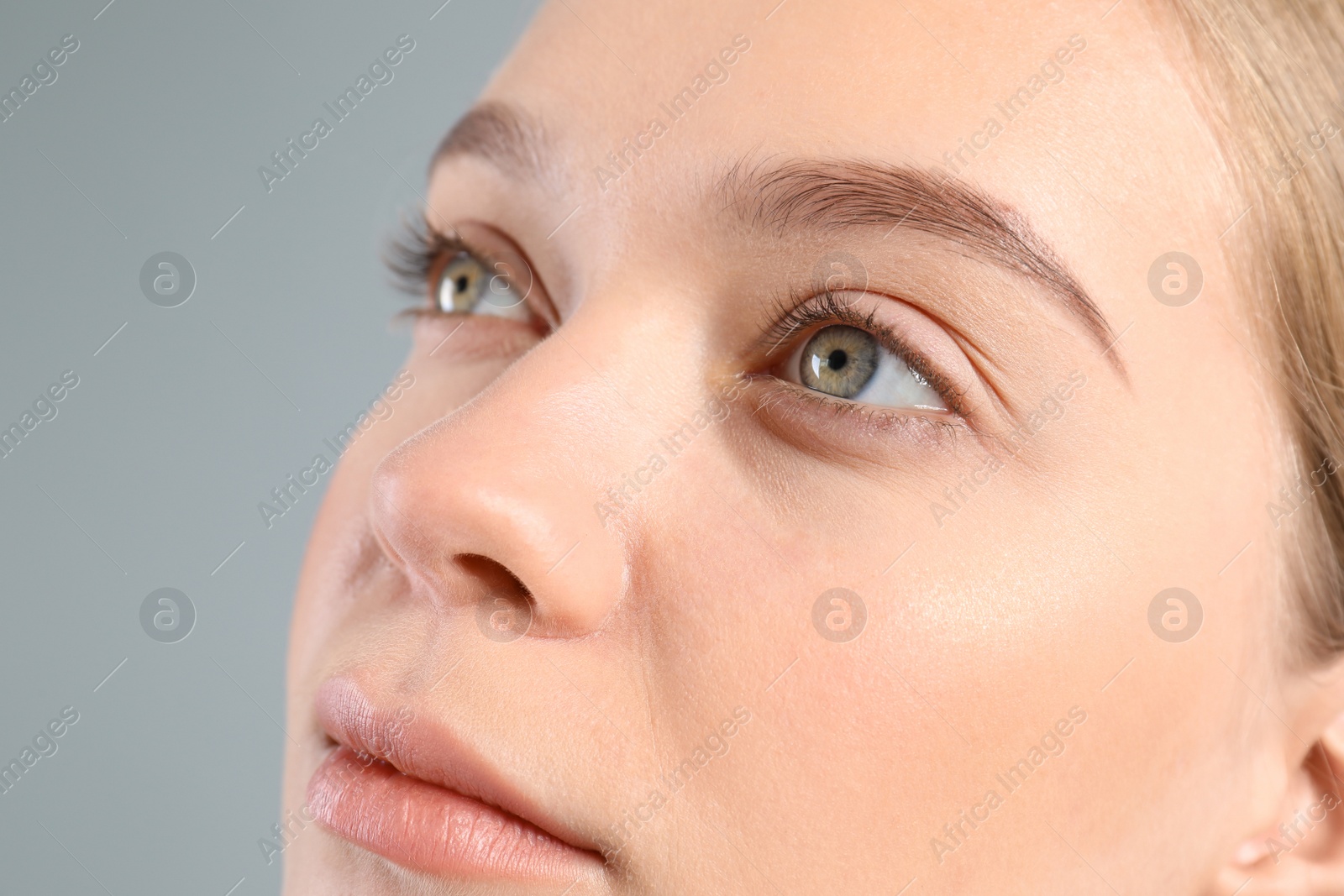 Photo of Young woman with beautiful natural eyelashes on gray background, closeup