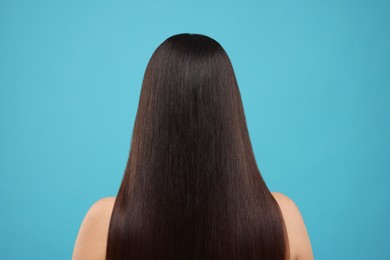 Photo of Woman with healthy hair after treatment on light blue background, back view