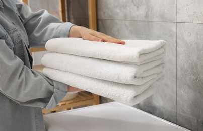 Photo of Woman with stack of clean towels indoors, closeup