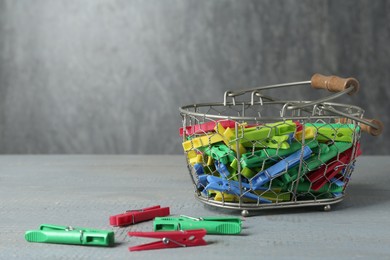 Basket with clothespins on light grey wooden table. Space for text