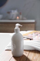 Photo of Wooden bath tray with shower gel, candle and fresh towel on tub indoors