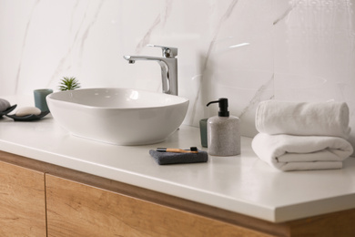 Toiletries and stylish vessel sink on light countertop in modern bathroom