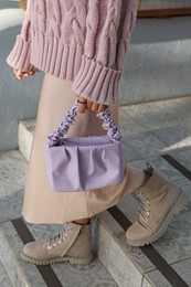 Photo of Fashionable woman with stylish bag on stairs outdoors, closeup