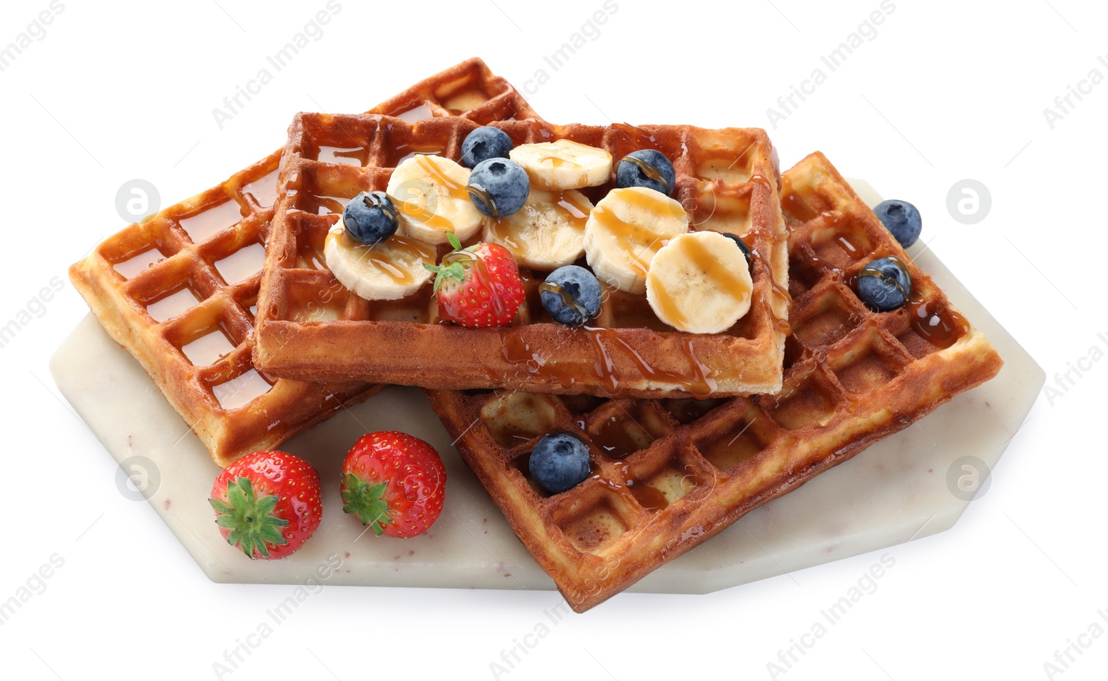 Photo of Board with delicious Belgian waffles, banana, berries and caramel sauce isolated on white