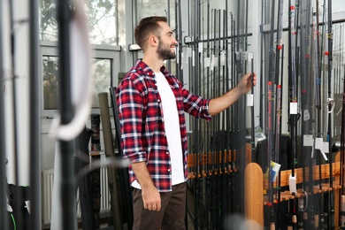 Photo of Man choosing fishing rod in sports shop