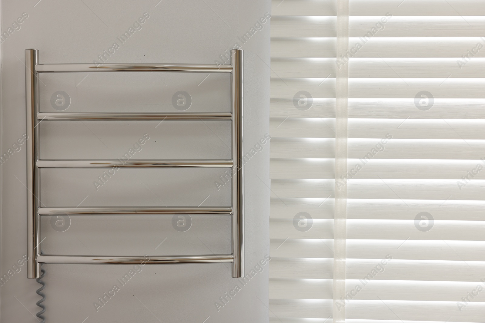 Photo of Heated towel rail on white wall in bathroom, space for text