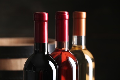 Bottles of different wine on dark background, closeup. Space for text