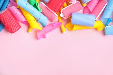 Photo of Many different hair curlers on pink background, flat lay. Space for text