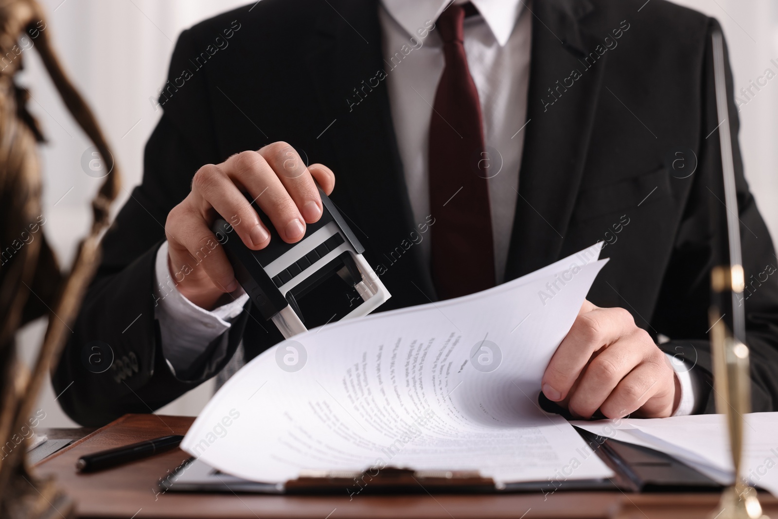 Photo of Notary stamping document at table in office, closeup