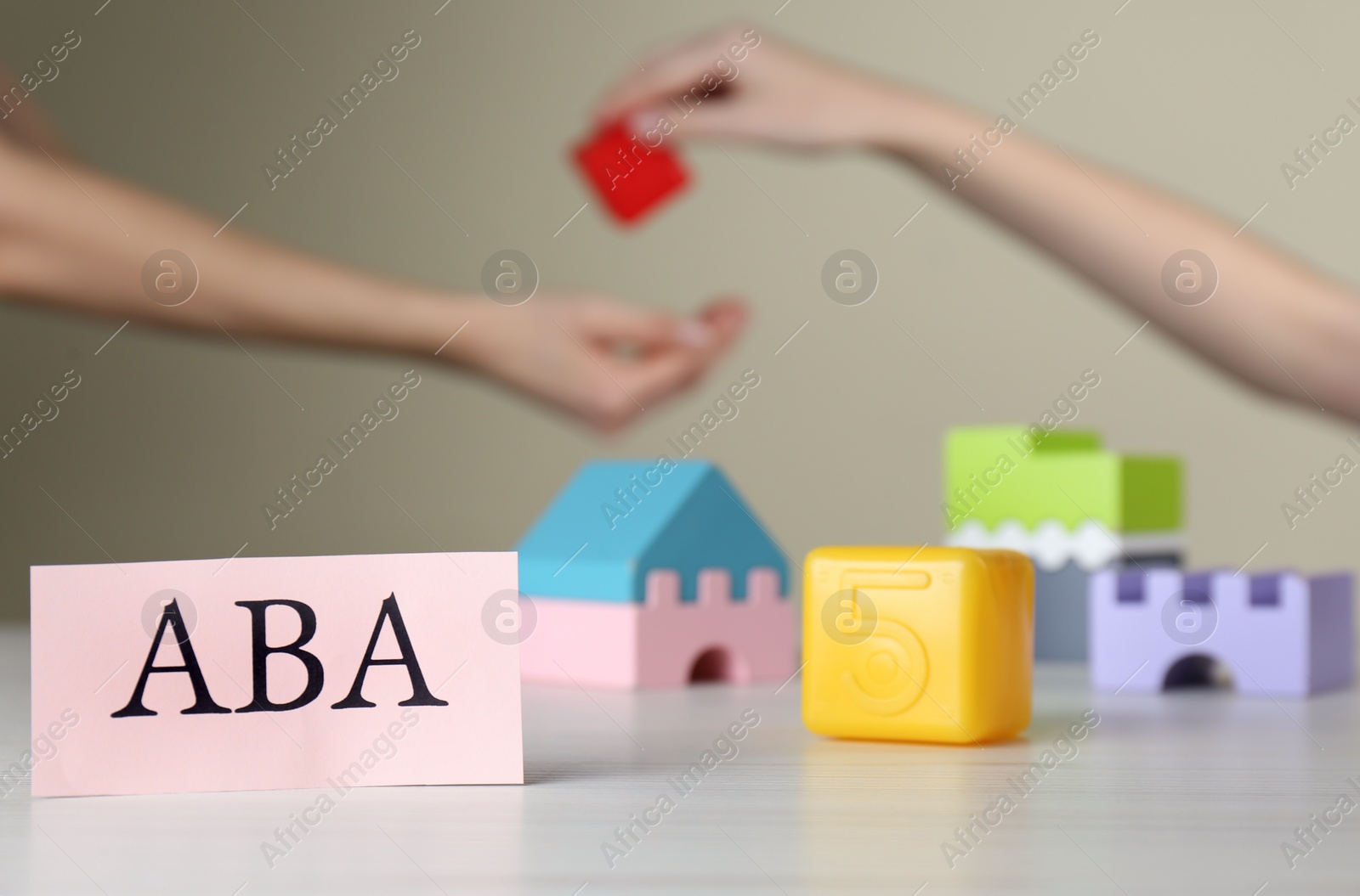 Photo of Paper card with abbreviation ABA (Applied behavior analysis) and blocks on white table, space for text