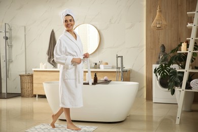 Photo of Beautiful young woman near tub in bathroom