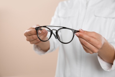 Photo of Female ophthalmologist with eyeglasses on light background, closeup. Space for text