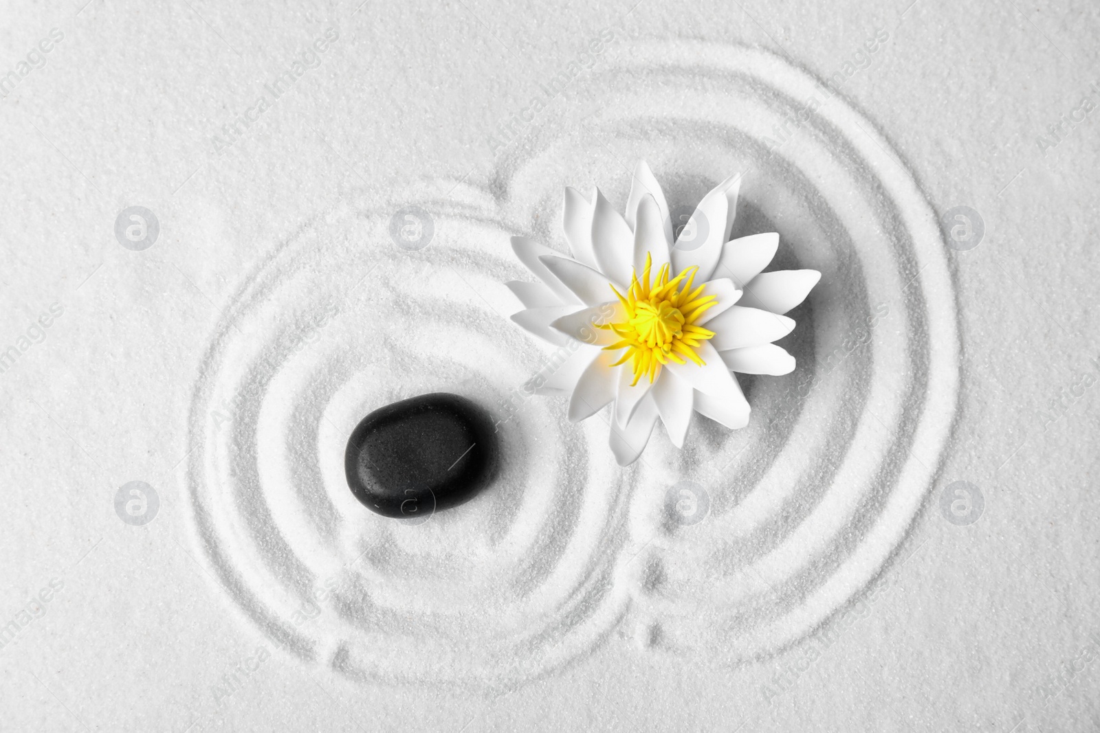 Photo of Zen garden. Beautiful lotus flower and stone on white sand, flat lay