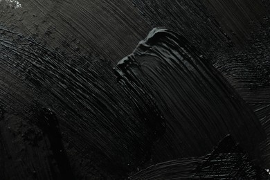 Photo of Beautiful strokes of black paint as background, closeup