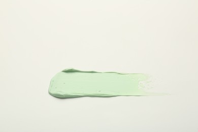 Photo of Stroke of green color correcting concealer on white background