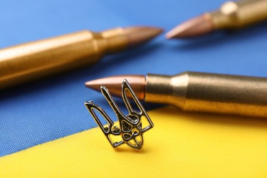 Photo of Ukrainian trident and bullets on national flag of Ukraine, closeup