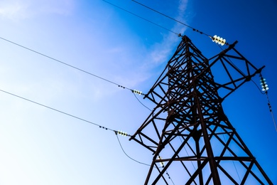 High voltage tower against beautiful blue sky, low angle view