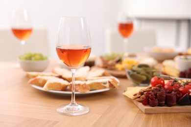 Photo of Rose wine and assorted appetizers served on wooden table indoors, selective focus. Space for text