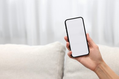 Photo of Woman holding smartphone in hand at home, closeup. Space for text