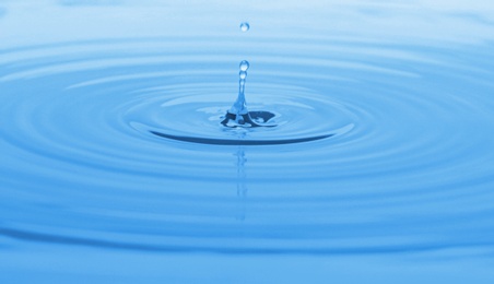 Photo of Splash of blue water with drop, closeup