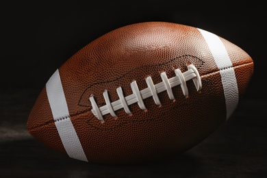 Photo of New American football ball on table against dark background