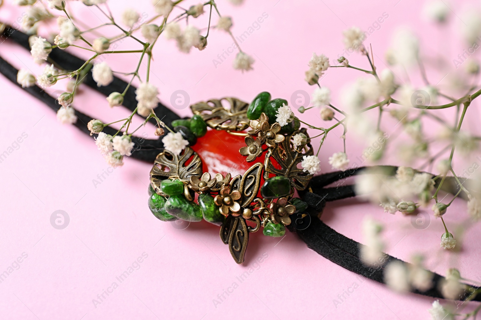 Photo of Beautiful bracelet with cornelian gemstone and flowers on pink background