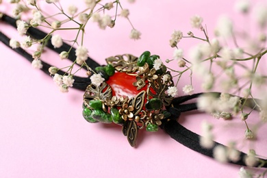 Photo of Beautiful bracelet with cornelian gemstone and flowers on pink background