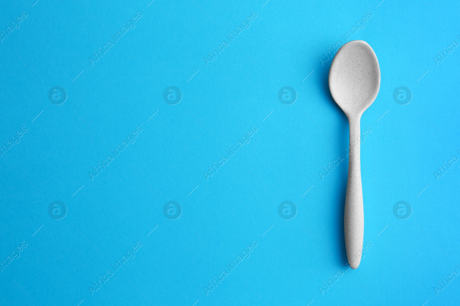 Photo of Clean empty spoon on blue background, top view. Space for text