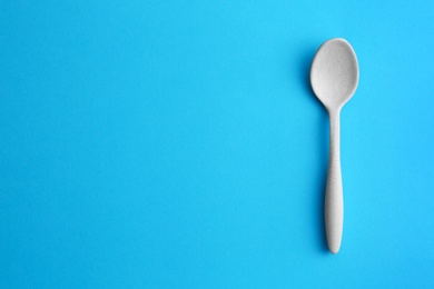 Clean empty spoon on blue background, top view. Space for text