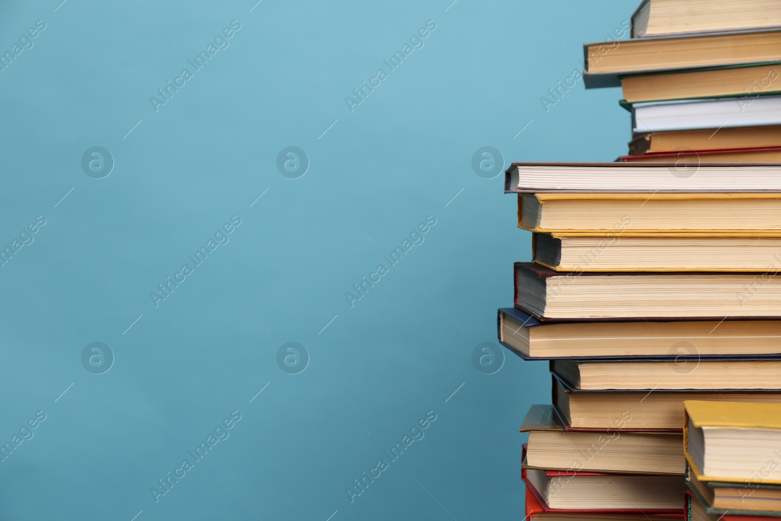 Photo of Many hardcover books on turquoise background, space for text. Library material