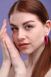 Portrait of beautiful woman with freckles on purple background, closeup