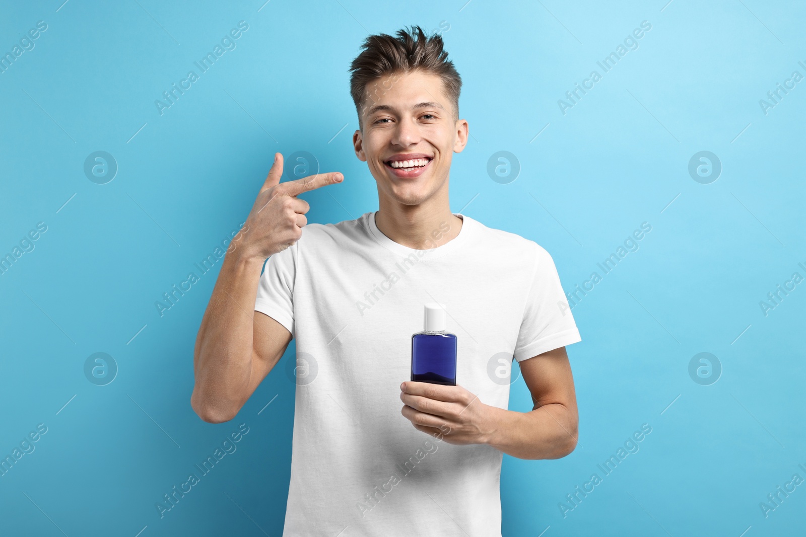 Photo of Young man with mouthwash on light blue background