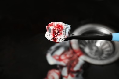 Toothbrush with paste and blood over sink, closeup. Gum inflammation