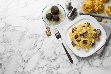 Tasty tagliatelle with truffle served on white marble  table, flat lay. Space for text