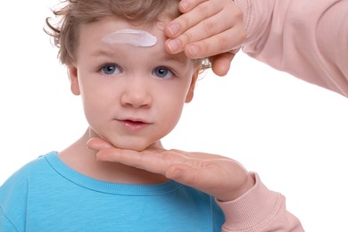 Photo of Mother applying ointment onto her son`s forehead on white background, closeup