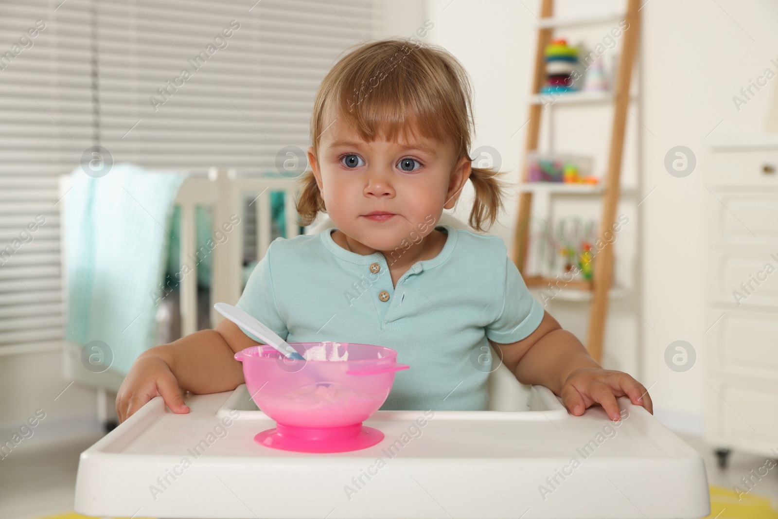 Photo of Cute little child eating tasty yogurt with spoon at home