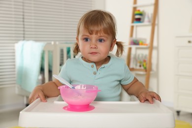 Cute little child eating tasty yogurt with spoon at home