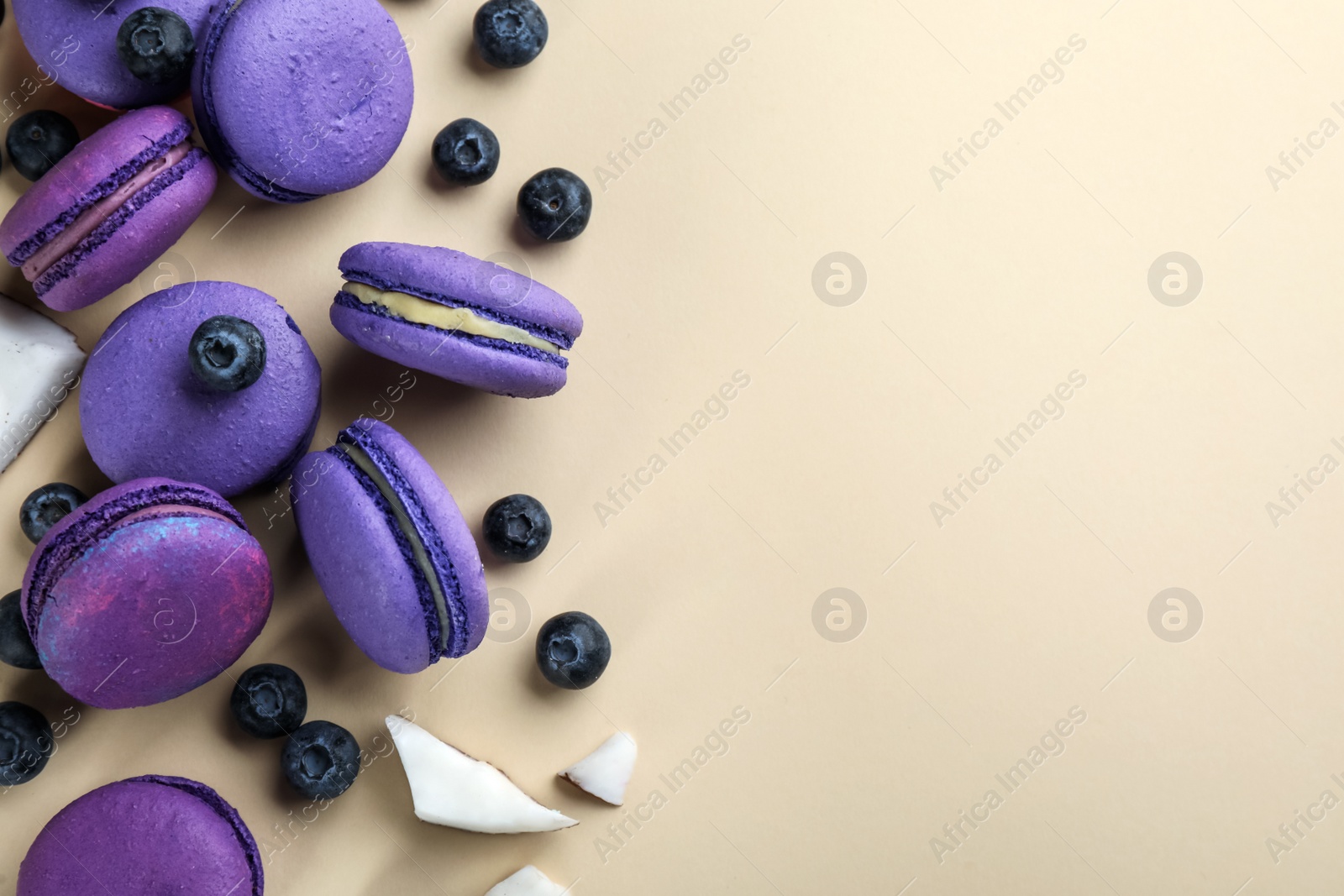 Photo of Flat lay composition with purple macarons, blueberries and pieces of coconut on beige background. Space for text