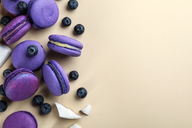 Photo of Flat lay composition with purple macarons, blueberries and pieces of coconut on beige background. Space for text