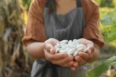 Photo of Woman holding white beans in hands outdoors, closeup