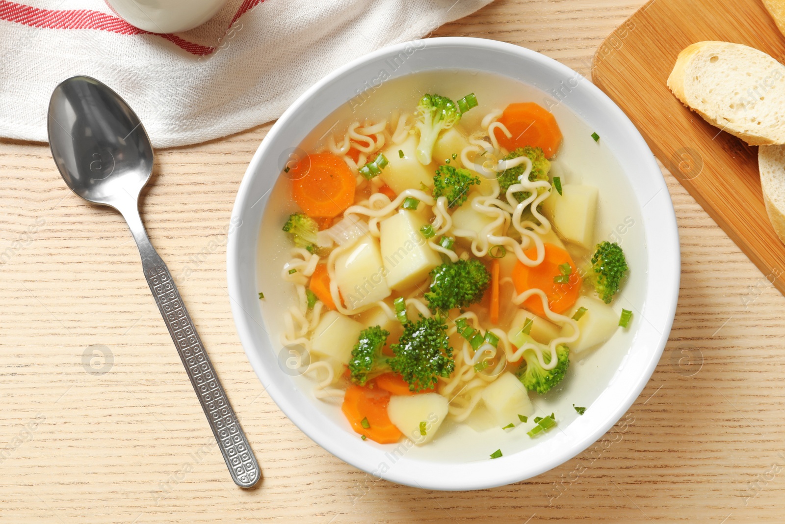 Photo of Bowl of fresh homemade vegetable soup served on wooden table, flat lay