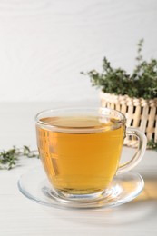 Aromatic herbal tea with thyme on white wooden table