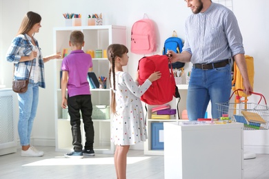 Children with parents choosing school stationery in store