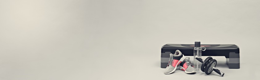 Image of Step platform, abdominal wheel, water bottle and sneakers on light background, space for text. Banner design