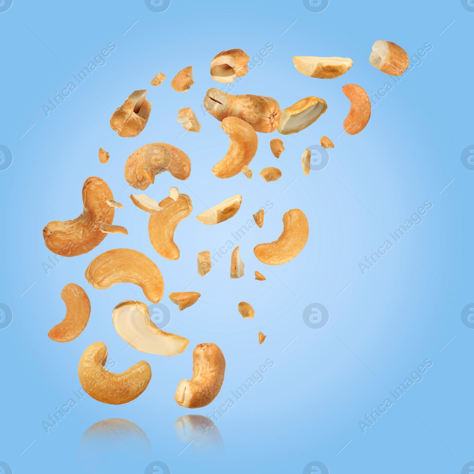 Image of Tasty cashew nuts flying on light blue background