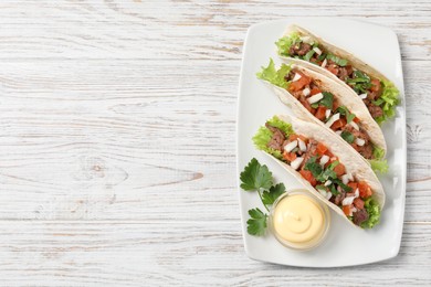 Photo of Delicious tacos with meat and vegetables served on wooden table, top view. Space for text